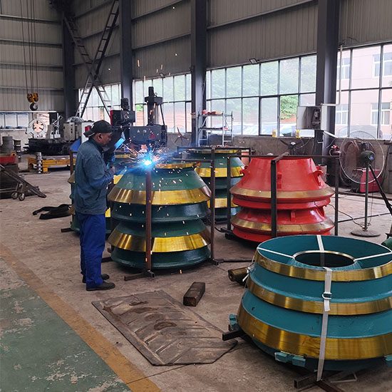 Worker performing final welding on cone crusher mantle before shipment