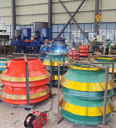 Cone crusher mantles stored on protective steel frames in factory